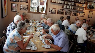 Et bilde innendørs av mennesker som inntar et måltid